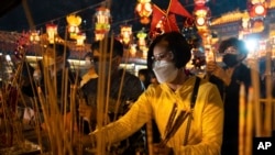 Fieles con mascarillas prenden sus primeras varitas de incienso del año para orar en el Templo Wong Tai Sin, el sábado 21 de enero de 2023 en Hong Kong para celebrar el Año Nuevo Lunar y el inicio del Año del Conejo.