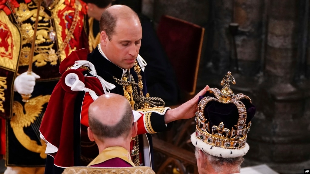 El príncipe Guillermo de Gran Bretaña toca la corona de San Eduardo en la cabeza del rey Carlos III durante su ceremonia de coronación en la Abadía de Westminster, Londres, el sábado 6 de mayo de 2023.