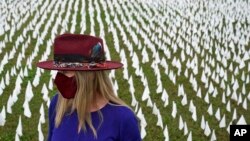 Artist Suzanne Brennan Firstenberg stands among thousands of white flags planted in remembrance of Americans who have died of COVID-19, part of her art installation, near Robert F. Kennedy Memorial Stadium in Washington, D.C., Oct. 27, 2020.