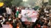 A protestor holds up a placard and sits with others in New Delhi, India, Dec. 19, 2019. 