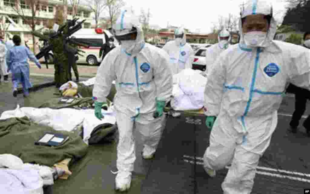 Futaba Kosei Hospital patients who might have been exposed to radiation are carried into the compound of Fukushima Gender Equality Centre in Nihonmatsu in Fukushima Prefecture (state) after being evacuated from the hospital in Futaba town near the trouble