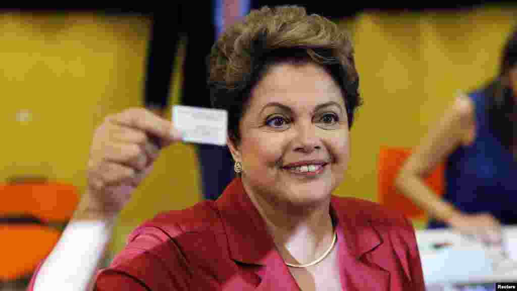 Brazil's President and Workers' Party (PT) presidential candidate Dilma Rousseff holds up her voter's card before voting in the runoff election in Porto Alegre, Oct. 26, 2014. 