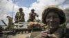  In this photo released by the African Union-UN Information Support Team, Kenyan soldiers with the African Union Mission in Somalia sit on top of an armored vehicle in Saa'moja, north-west of the port city of Kismayo, October 1, 2012. 