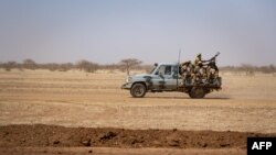 FILE - Burkina Faso soldiers patrol atop a pick-up truck on the road between Dori and Goudebo, in Burkina Faso, Feb. 3, 2020. 