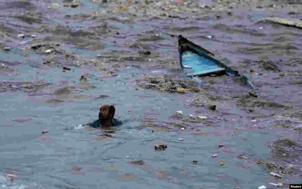 A fisherman swims to shore after his boat capsized due to high waves ahead of the expected landfall of Cyclone Vayu at Veraval, India.