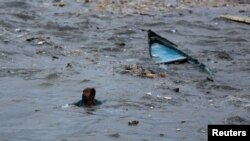 A fisherman swims to shore after his boat capsized due to high waves ahead of the expected landfall of Cyclone Vayu at Veraval, India, June 12, 2019. 