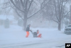 A man is bundled up against bitter wind and blowing snow as he operates a snowblower, Jan. 30, 2019, in Buffalo, N.Y. The area received more than a foot of snow since Tuesday and was under a blizzard warning.