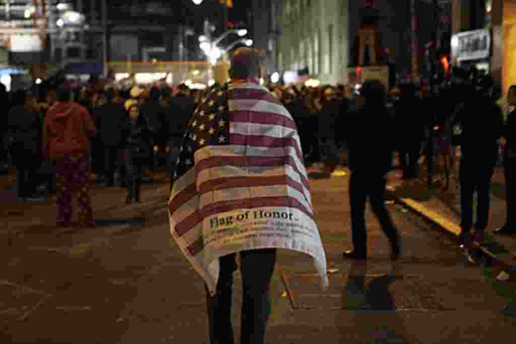 A man carries an American flag while walking to join a crowd gathered to celebrate the death of Osama bin Laden at the construction site at Ground Zero in New York, May 2, 2011.