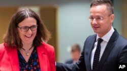 European Commissioner for Trade Cecilia Malmstrom, left, talks with Hungary's Foreign Minister Peter Szijjarto during an EU foreign affairs council on trade at the Europa building in Brussels, Belgium, May 22, 2018. 