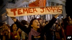 FILE - A woman holds a sign that reads in Portuguese; "Never Temer!" to protest the government of acting President Michel Temer in Rio de Janeiro, Brazil, May 13, 2016.