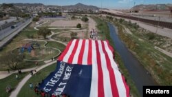 Migrantes venezolanos portan una inmensa bandera de EEUU en una protesta contra la nueva política de inmigración de Estados Unidos cerca del Río Bravo en Cuidad Juárez, México, el 31 de octubre de 2022.
