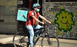 A delivery man cycles past a street art in Sydney, May 8, 2020.