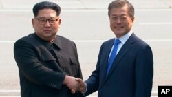 Pemimpin Korea Utara Kim Jong-un (kiri) bersalaman dengan Presiden Korea Selatan Moon Jae-in di garis demarkasi, Jumat (27/4). 