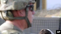 An Afghan girl stands near a U.S. soldier standing guard at a U.S. military checkpoint in Kuz district in Kunar (File)