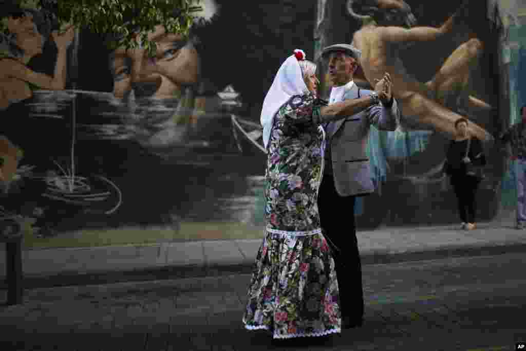 A couple dressed in traditional &#39;chulapo&#39; attire dances as they take part in a religious procession during festivities in honor of local patron San Lorenzo, Saint Lawrence, in Madrid.