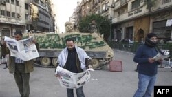 Người biểu tình chống chính phủ đọc báo phía trước một chiếc xe bọc thép ở Quảng trường Tahir ở thủ đô Cairo, ngày 2/2/2011