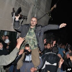 Anti-Syrian regime protesters hold up a Syrian army defector as they chant slogans against Syrian President Bashar Assad during an evening protest, in the Rastan area in Homs province, central Syria, on Monday Jan. 30, 2012.
