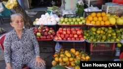 FILE - A woman sells fruit at a stand in Ho Chi Minh City.