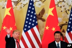 FILE - U.S. President Donald Trump waves next to Chinese President Xi Jinping after attending a joint press conference at the Great Hall of the People in Beijing, Nov. 9, 2017.