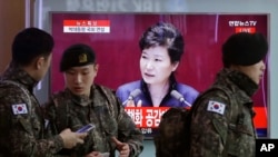South Korean army soldiers pass by a TV screen showing the live broadcast of South Korean President Park Geun-hye's speech, at the Seoul Railway Station in Seoul, South Korea, Tuesday, Feb. 16, 2016.