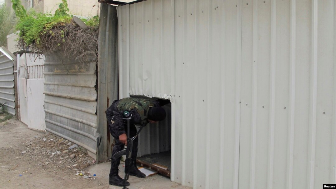 Seorang polisi Irak melihat gedung apartemen lokasi penembakan terjadi, di Baghdad 13 Juli 2014. Sekitar 29 orang, 20 di antaranya perempuan, tewas pada hari Sabtu malam di gedung apartemen di timus Baghdad oleh laki-laki bersenjata.