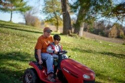 Caroline Clarin rides with Ali Patan, 7, as he drives her riding mower at her home in Dalton, Minn., Oct. 30, 2021.