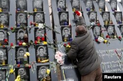 FILE - A man places flowers at a monument to the so-called "Heavenly Hundred," anti-government protesters killed during Ukraine's 2014 Maidan revolution, in Kyiv, Ukraine, Nov. 21, 2019.
