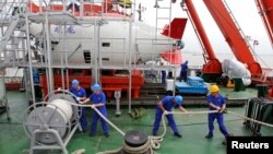 FILE - Staff work on a boat in front of the China's manned deep-diving submersible "Jiaolong" in Jiangyin, Jiangsu province July 1, 2011.