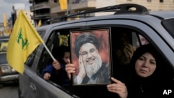 A Lebanese woman holds a portrait of slain Hezbollah leader Sayyed Hassan Nasrallah, as she sits in a car with her family on their way to check their village after the Israeli troops withdrew from it, in Bint Jbeil town, south Lebanon, Jan. 26, 2025.