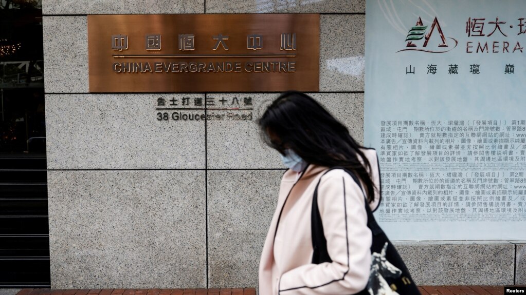 FILE - A woman walks in front of the China Evergrande Centre building sign in Hong Kong, China, Dec. 7, 2021