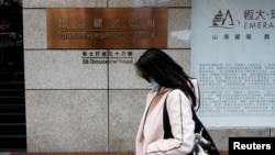 FILE - A woman walks in front of the China Evergrande Centre building sign in Hong Kong, China, Dec. 7, 2021