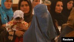 FILE - Women listen to a speech by Afghanistan's President Hamid Karzai during a district assembly gathering in Kabul on May 30, 2013.