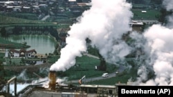 Cars drive on a road as steam rises from a geothermal power plant in Dieng, Central Java, Indonesia, Nov. 15, 2024. (AP Photo/Beawiharta)
