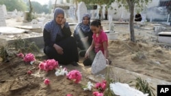 Palestinian Abir Shamaleh, left, mourns at the grave of her son Saher, killed in an Israeli strike. The family, saying he was a civilian, visit the cemetery in Gaza City July 28, 