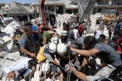 FILE - Members of the Syrian civil defense, known as the White Helmets, search for victims under the rubble following a reported airstrike on Maaret al-Numan in Syria's northwestern Idlib province, July 22, 2019.