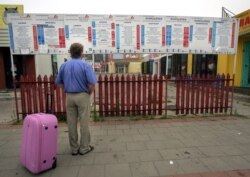 FILE - Andrzej looks at the timetable at an international bus station in Bialystok, eastern Poland, Aug. 8, 2006, before his wife leaves to work in England.