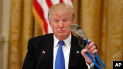 President Donald Trump holds up a Channellock locking plier during a "Made in America," roundtable event in the East Room of the White House, Wednesday, July 19, 2017, in Washington. 