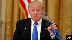 President Donald Trump holds up a Channellock locking plier during a "Made in America" roundtable event in the East Room of the White House, July 19, 2017, in Washington. 