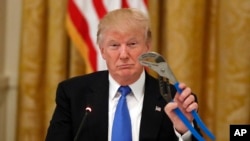 President Donald Trump holds up a Channellock locking plier during a "Made in America," roundtable event in the East Room of the White House, Wednesday, July 19, 2017, in Washington. 