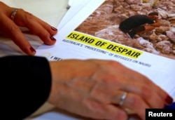 Anna Neistat, senior director for research with Amnesty International, talks to journalists as she holds a copy of a report she co-authored titled 'Island of Despair - Australia's "Processing" of Refugees on Nauru,' in Sydney, Australia, October 17, 2016