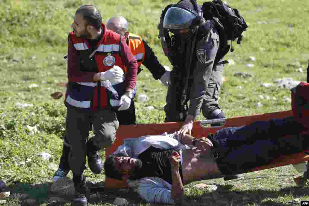 An Israeli soldier attempts to detain an injured Palestinian demontrator as he&#39;s carried on a stretcher by Palestinian Civil Defense volunteers in the West Bank town of Birzeit, near Ramallah, during a protest by students of the Birzeit University against the arrest of the the head of Palestinian student council by an Israeli undercover commando.