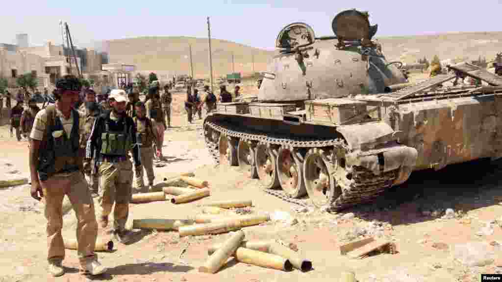 Free Syrian Army fighters inspect munitions and a tank that belonged to forces loyal to Syria's President Bashar al-Assad after they seized Khanasir, August 26, 2013. 
