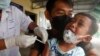 A young boy, held by his father, reacts as he receives a second dose of the Sinovac's COVID-19 vaccine at a Krang Thnung health center outside Phnom Penh, Cambodia, Monday, Nov. 15, 2021. (AP Photo/Heng Sinith)