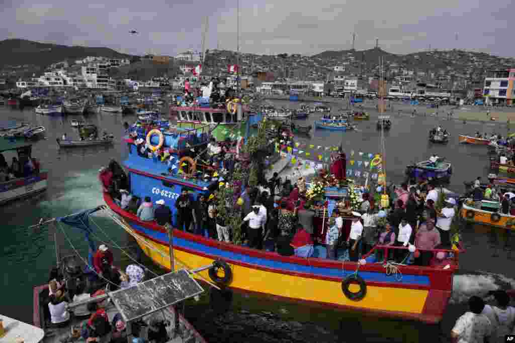 Devotos de San Pedro, el santo patrón católico de los pescadores, llevan su imagen en un bote durante una procesión por tierra y mar que marca la celebración del día de los pescadores en el puerto de Pucusana, Perú, el jueves 29 de junio de 2023.