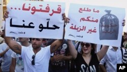 Protesters hold up signs against the Lebanese government during a rally against the ongoing trash crisis in Beirut, Aug. 8, 2015. The sign at left reads in Arabic, "We're sick of you, go away," and, at right, "Nothing comes from you but garbage."