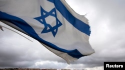 FILE - An Israeli flag flies on a hill near Bethlehem, March 17, 2013. 