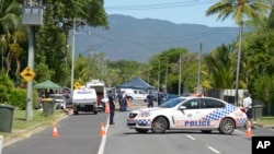 Polisi memblokir jalan di luar sebuah rumah tempat delapan anak ditemukan tewas di Manoora, pinggiran kota Cairns, Australia (19/12). (AP/Graeme Bint)