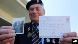 World War II veteran Bill Ridgewell, 94, shows a picture of himself at the age of 16 in uniform and a postcard he got from a French student Marion Nivard and others in Shaftesbury, England, May 6, 2020. 