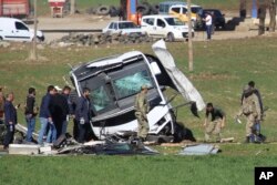 Những thành viên của lực lượng quân đội Thổ Nhĩ Kỳ đứng quanh một chiếc xe buýt đã bị phá hủy trong một vụ đánh bom trên tuyến đường nối thành phố Diyarbakir và Bingol ở đông nam Thổ Nhĩ Kỳ.