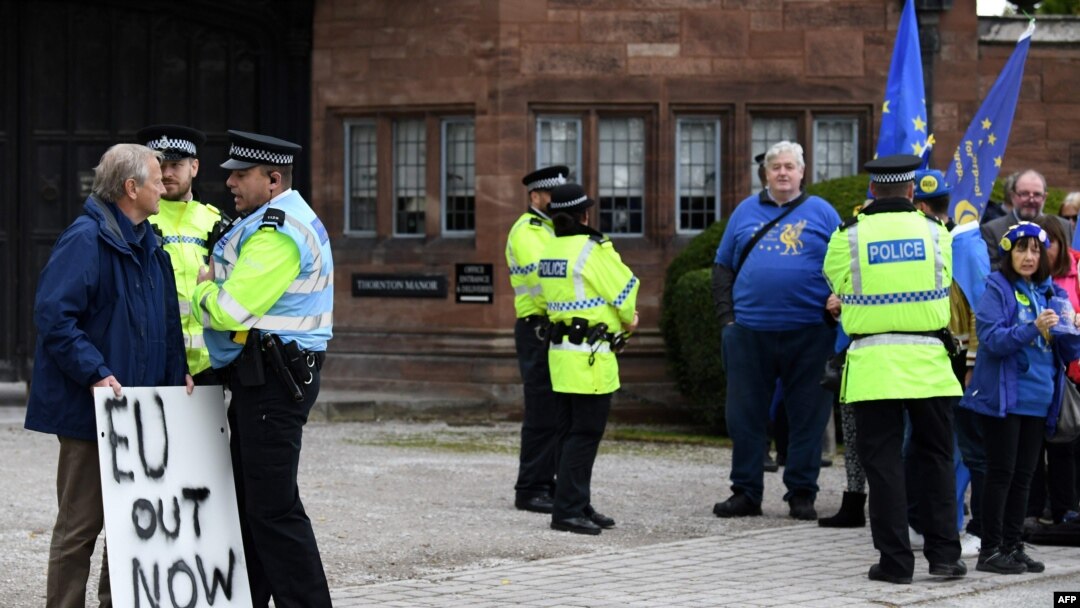 A lone pro-Brexit demonstrator, left, stands opposite anti-Brexit protesters outside Thornton Manor Hotel, Oct. 10, 2019, where Britain's Prime Minister Boris Johnson and Ireland's Prime Minister Leo Varadkar were meeting for Brexit talks.